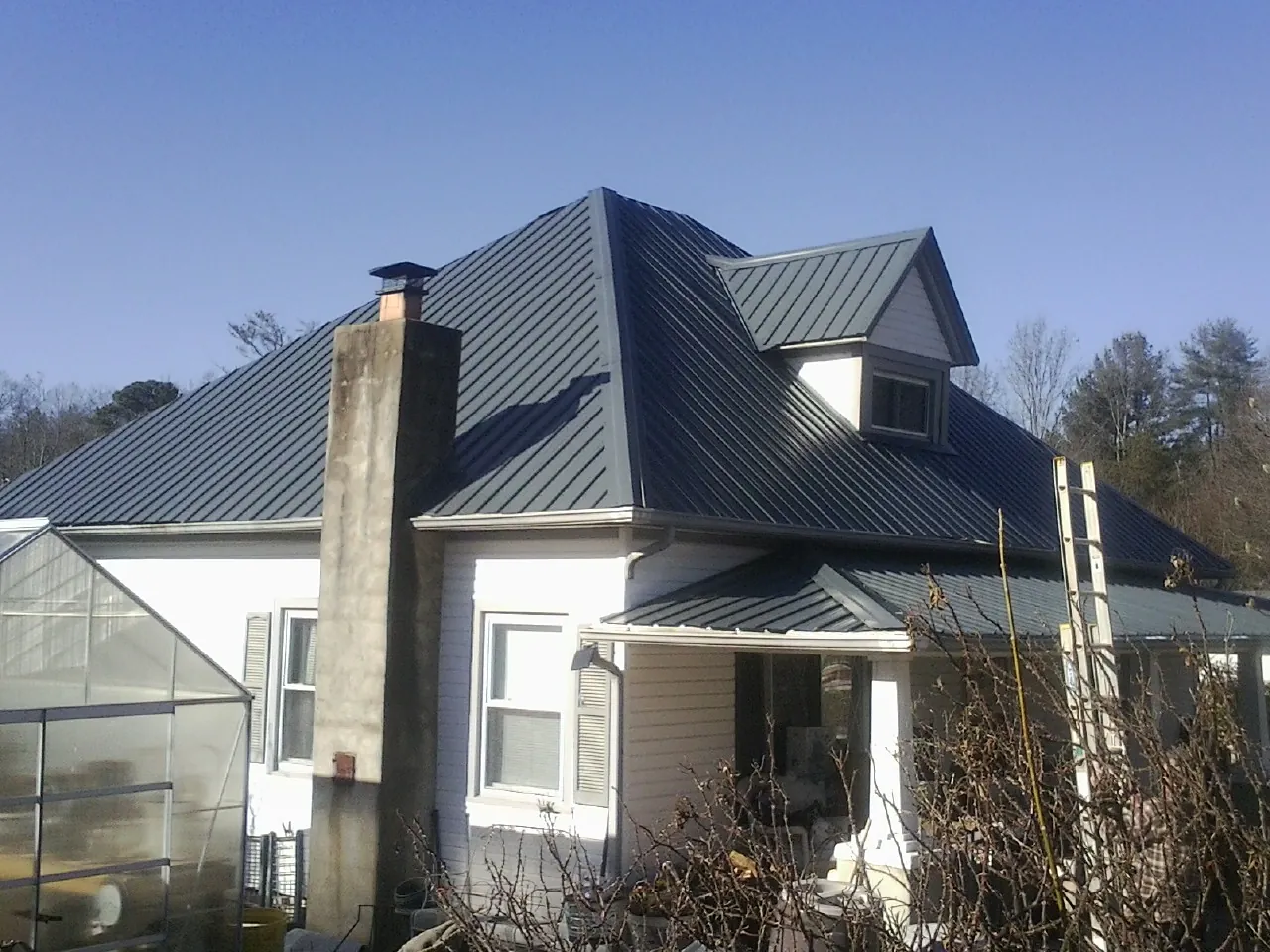 Dark blue standing seam metal roof on a white farmhouse with dormer — Slate & Tile Roof Repair by Roofing Brothers in Silt