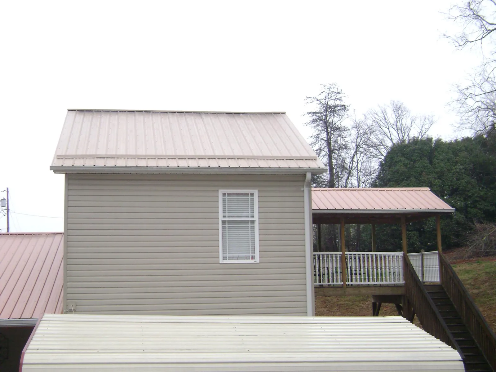 Tan metal roofs on a two story addition and attached porch, from a Roof Replacement job in Silt